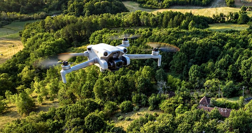 Drone de cartographie en vol au-dessus d’un massif forestier et de prairies